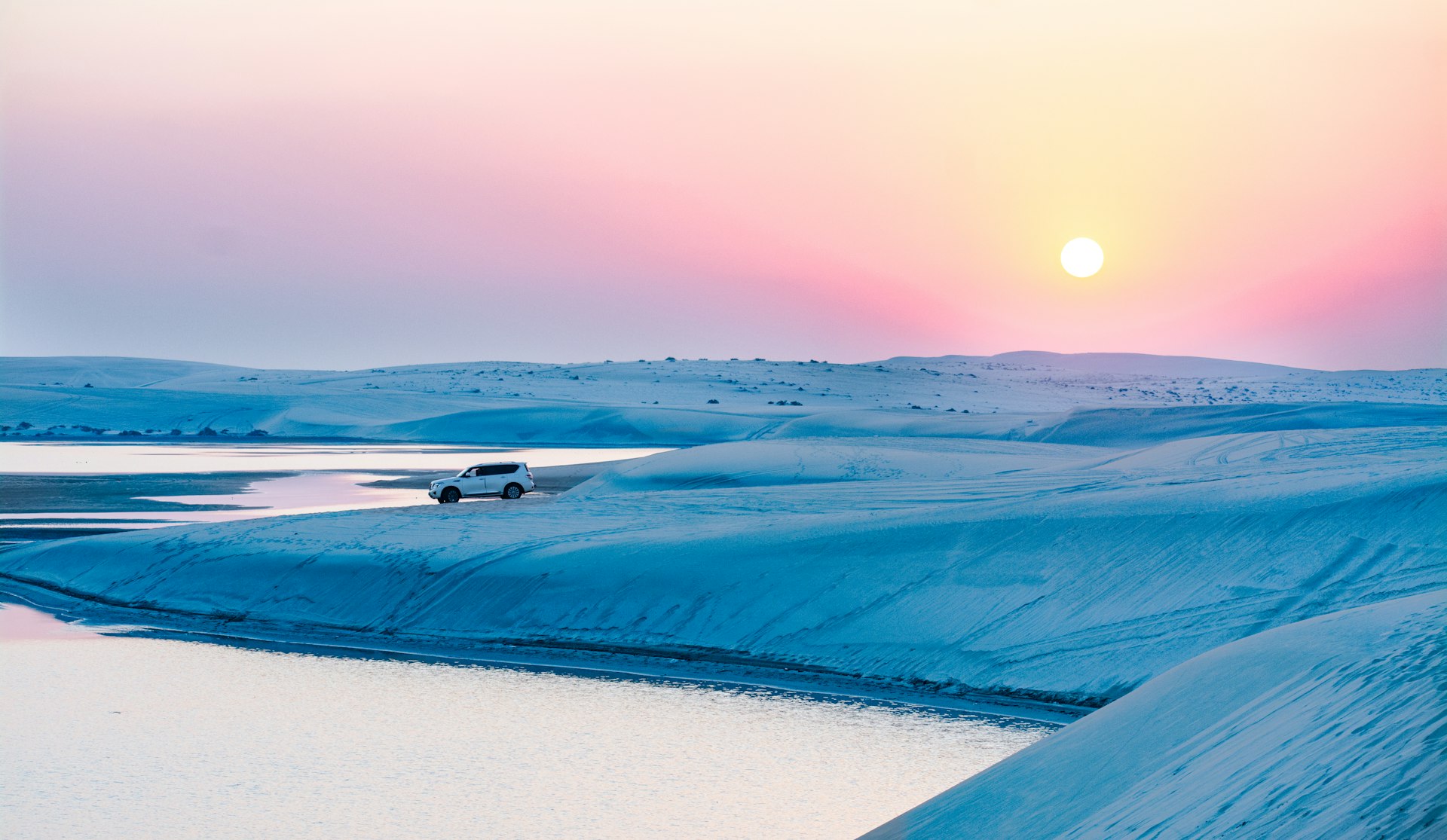 white SUV on white snow-capped field beside body of water during daytime