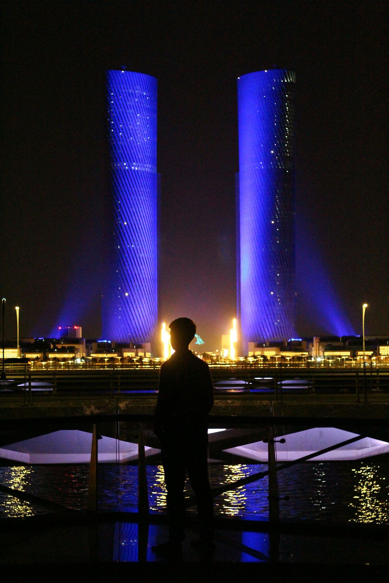 a man standing in front of a body of water at night